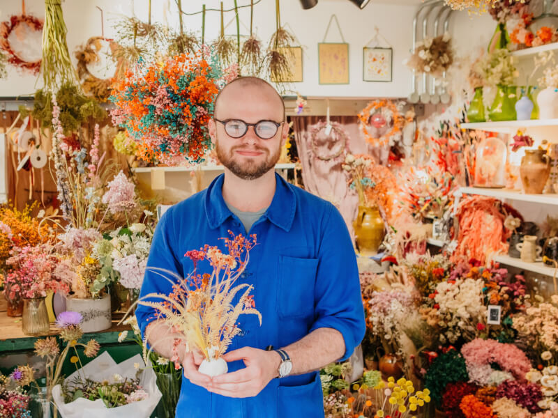 man posing with dried flower arrangement
